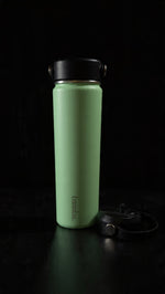 Load image into Gallery viewer, Green bamba water bottle with black lid on a dark background
