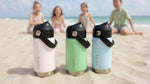 Load image into Gallery viewer, Three insulated bamba kids drink bottles on a sandy beach with children in the background.
